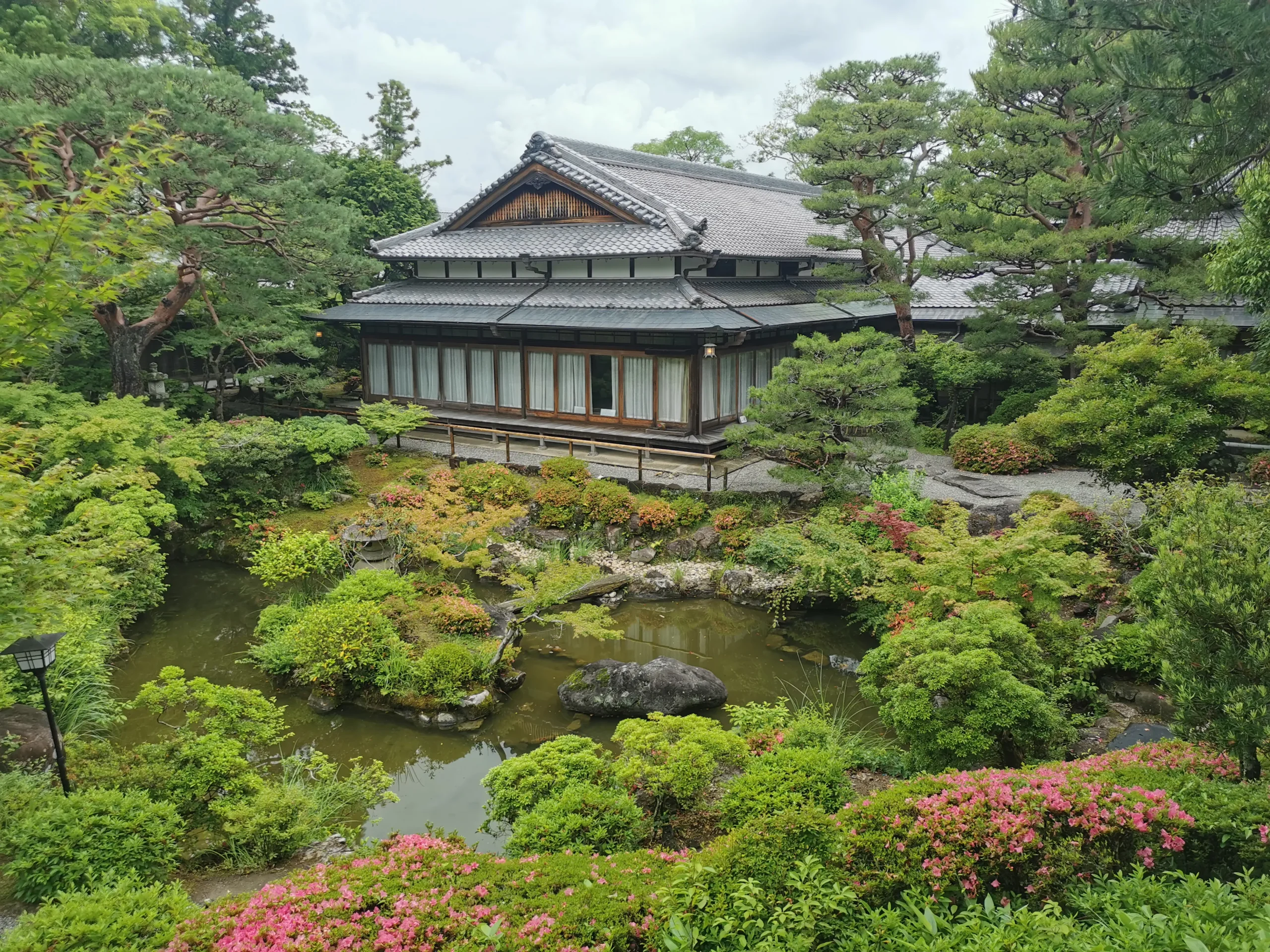 Pavillon traditionnel japonais entouré d’étang et de végétation à Yoshiki-en