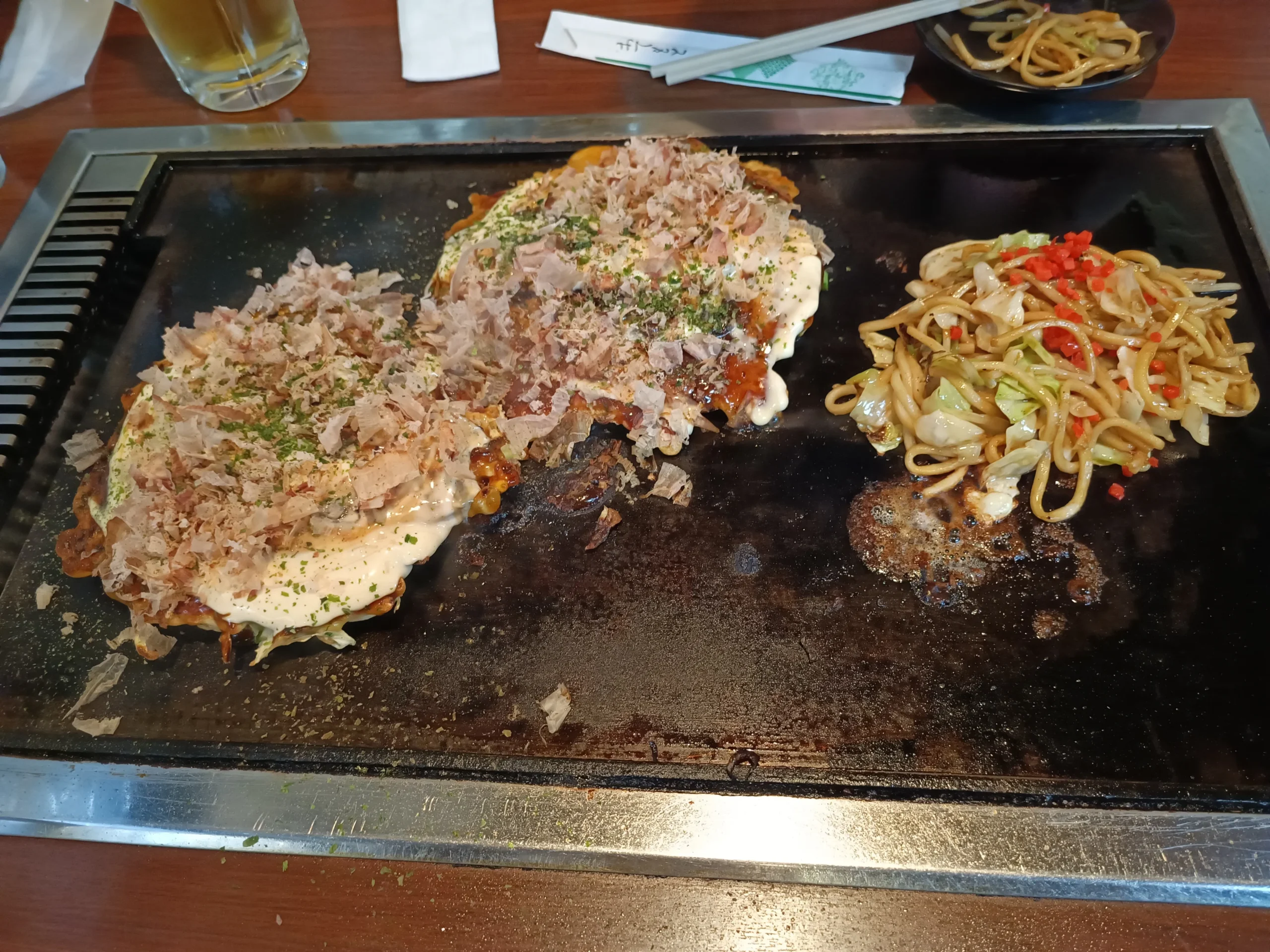 Okonomiyaki et yakisoba sur une plaque chauffante dans un restaurant à Osaka