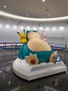 Photo de ronflex avec pikachu et mew à gauche et à droite de ses épaules