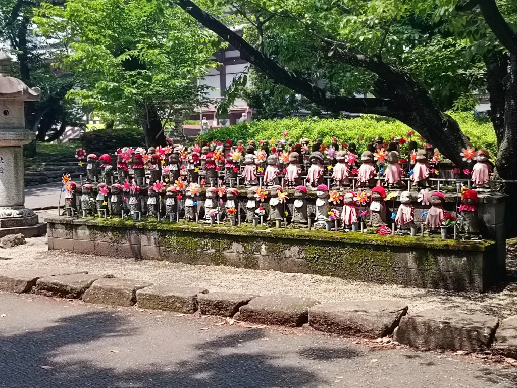 Statues de Jizō décorées de bonnets rouges, de bavoirs et de moulins à vent colorés dans l'enceinte du temple Zōjō-ji à Tokyo